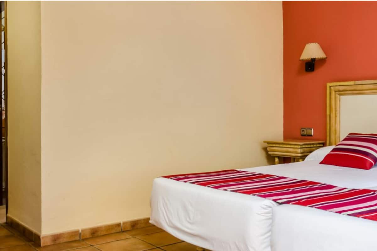 A hotel room with a large bed, a nightstand, a lamp, and a decorative wall piece.