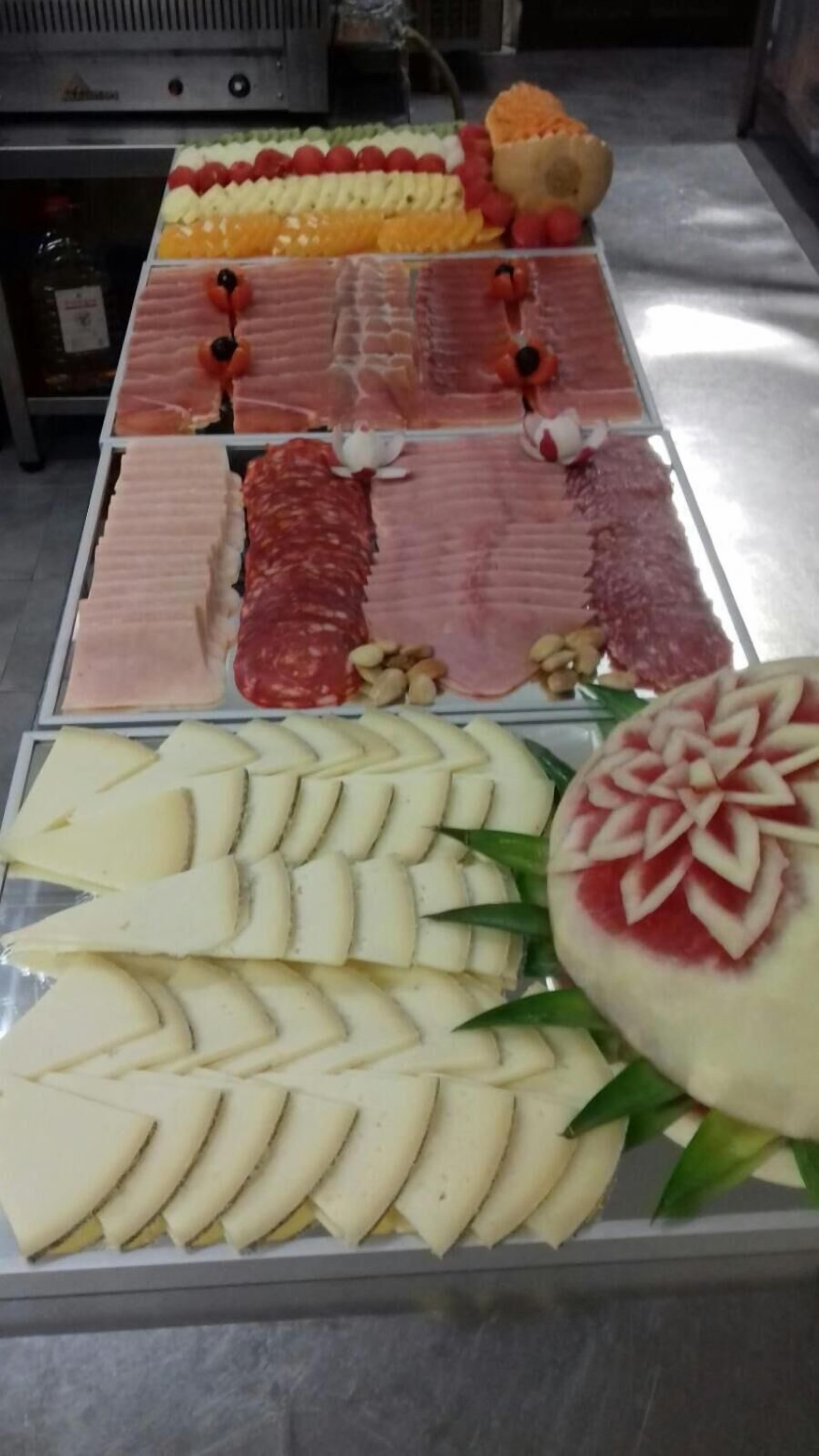 A display of various food items including sliced meats, cheeses, and fruits.