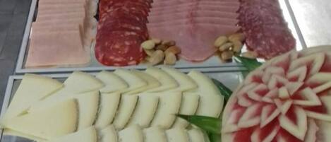 Una exhibición de diversos alimentos, como embutidos, quesos y frutas.