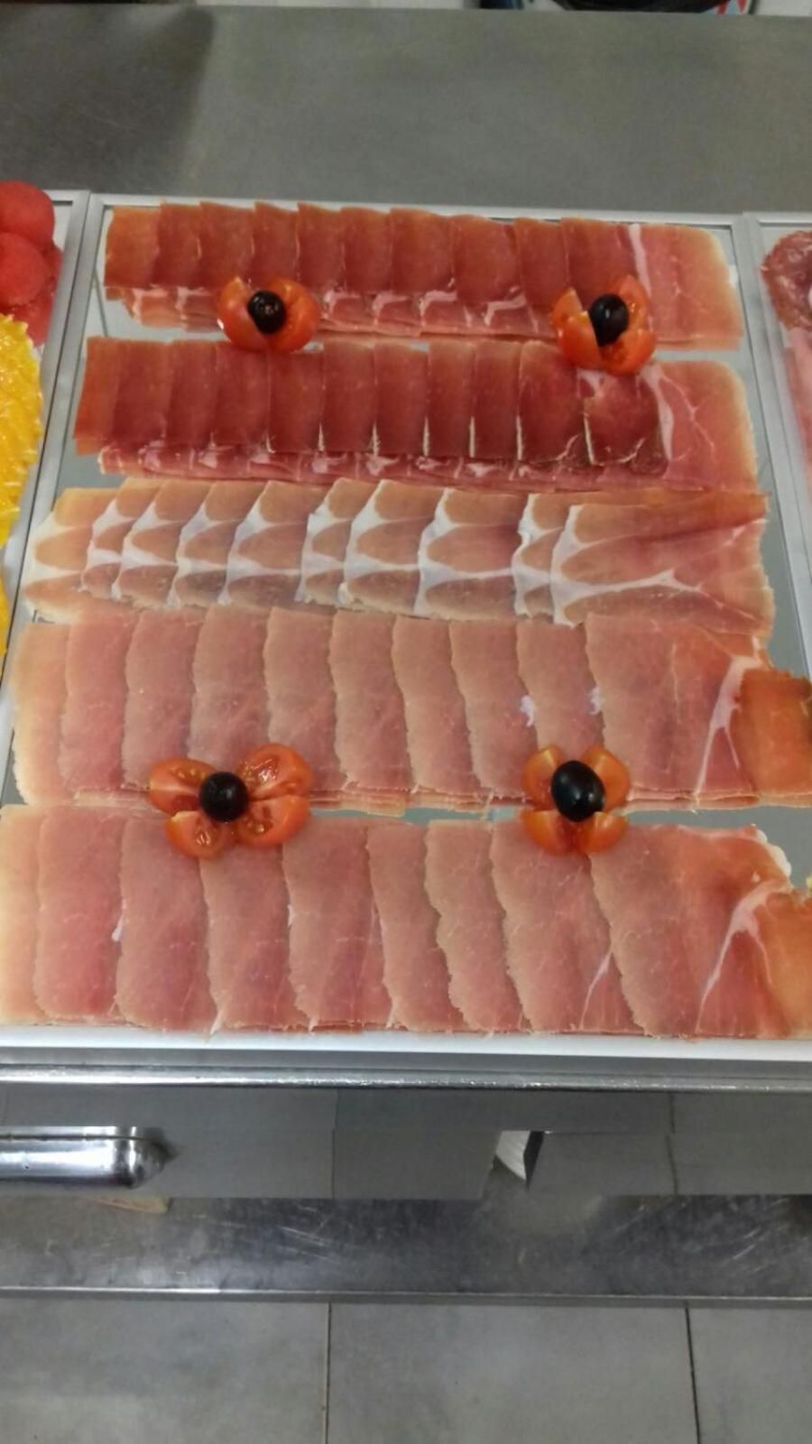 Een presentatie van plakjes vleeswaren, kersen tomaten en olijven.