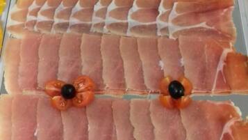 A display of sliced meats with cherry tomatoes and olives.