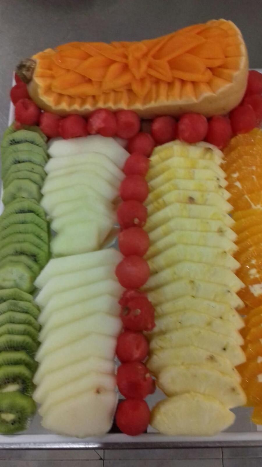 Une assiette de fruits comprenant différents fruits coupés en tranches et disposés selon un motif.