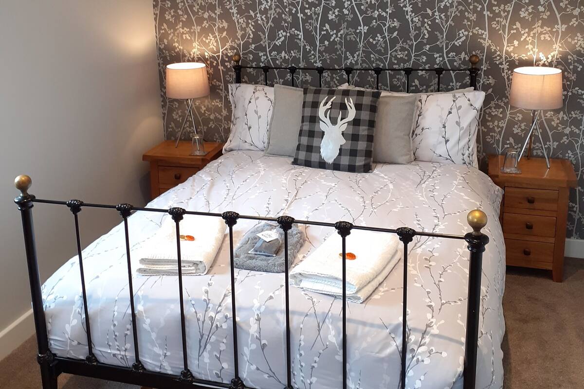 A bed with a metal frame, two bedside tables, and a wall with a tree pattern.