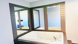 Un baño moderno con una bañera grande, un espejo y vistas al mar.
