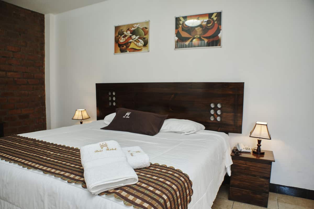 A neatly made bed with a striped bedspread, two pillows, and two bedside lamps.
