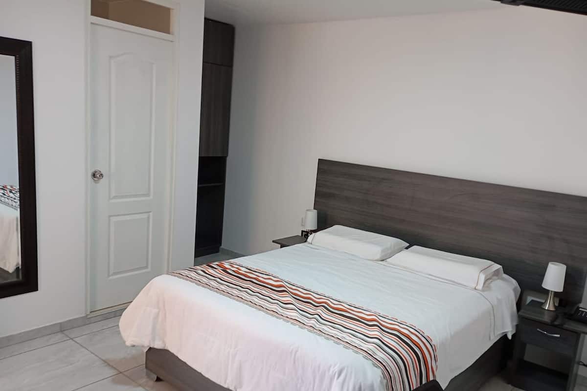 A bedroom with a bed, nightstands, a mirror, and a wardrobe.