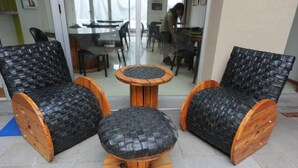 A seating area with two black woven chairs and a matching ottoman, all with wooden bases and armrests. - Hostel Unico (La Plata)