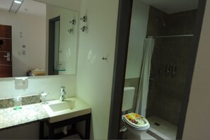 A bathroom with a shower, toilet, sink, and mirror. - Hostel Unico (La Plata)