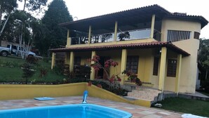 Une maison avec une piscine, une véranda et un véhicule garé à proximité.