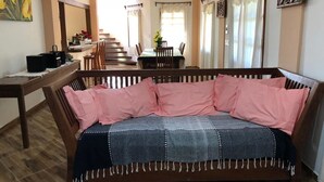 Un salon avec un canapé, un plancher en bois, une table à manger avec des chaises et un escalier menant à un autre niveau.