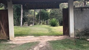 Une entrée couverte mène à une propriété appelée « St. Tito Damasiu », et un chemin de terre y conduit jusqu’à une zone herbeuse.