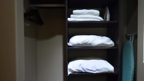 A closet with shelves holding folded clothes and a hanging rack. - Hotel Suites del Sol (Tijuana)