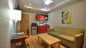 A compact living space with a kitchenette, a dining table, a sofa, and a ceiling fan. - Hotel Suites del Sol (Tijuana)