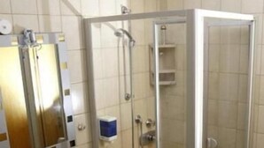 A bathroom with a glass-enclosed shower, a sink with a mirror, and a towel rack. - Hotel Restaurant Pempel (Grossalmerode)