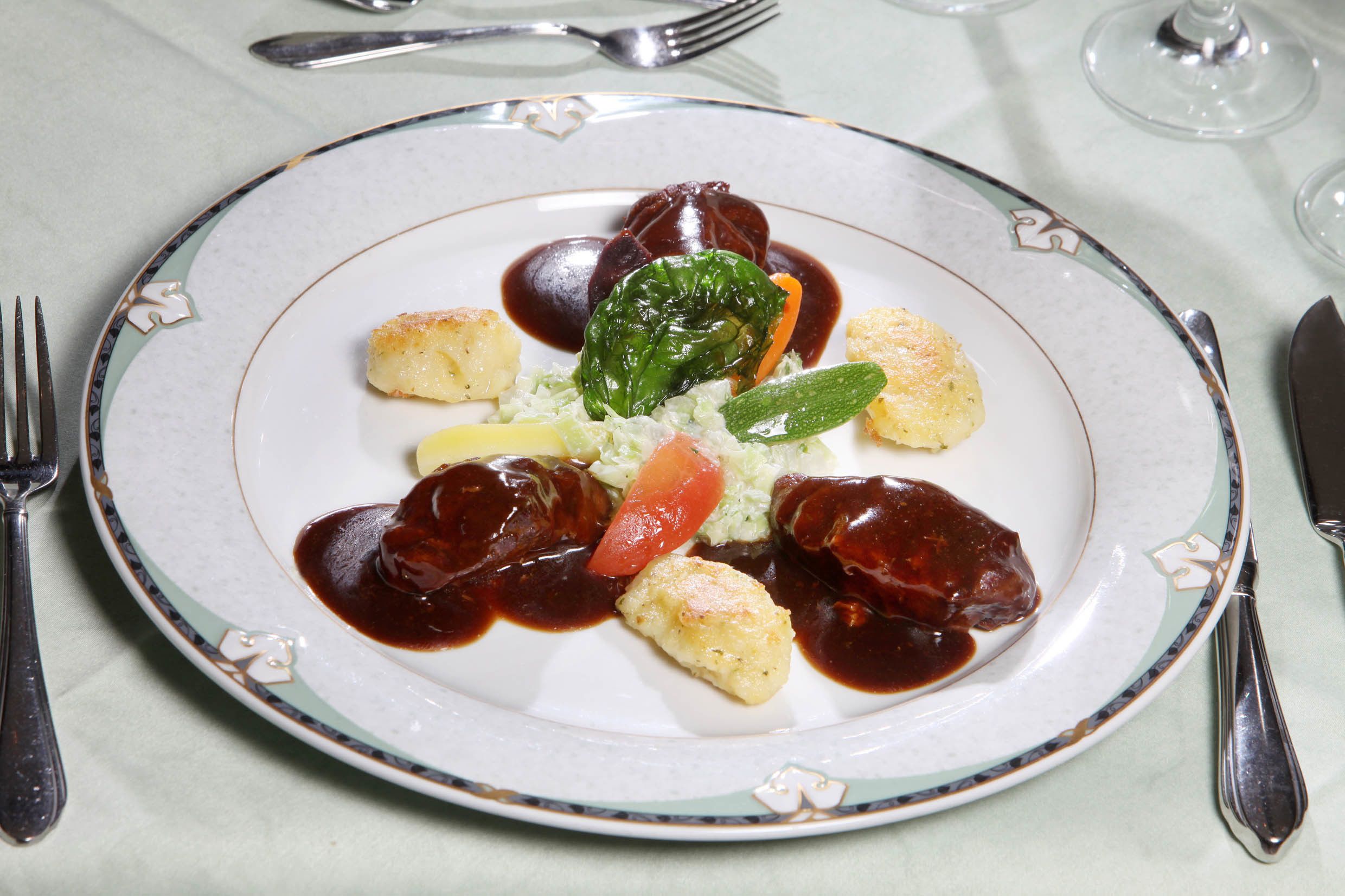 Un plato de comida con diferentes ingredientes, incluyendo carne, verduras y salsa.