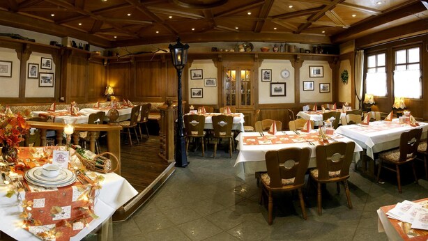 A restaurant with multiple tables set for dining, wooden walls, and framed pictures on the walls. - Hotel Restaurant Pempel (Grossalmerode)