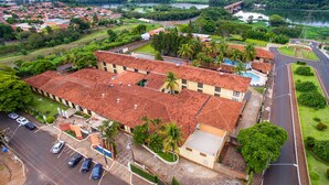 A large building with a red-tiled roof, surrounded by a parking lot and greenery.