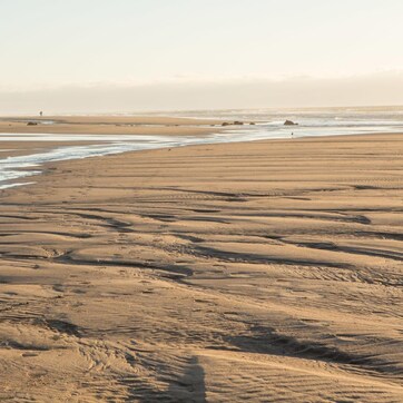 A wide sandy beach with gentle waves lapping at the shore.
