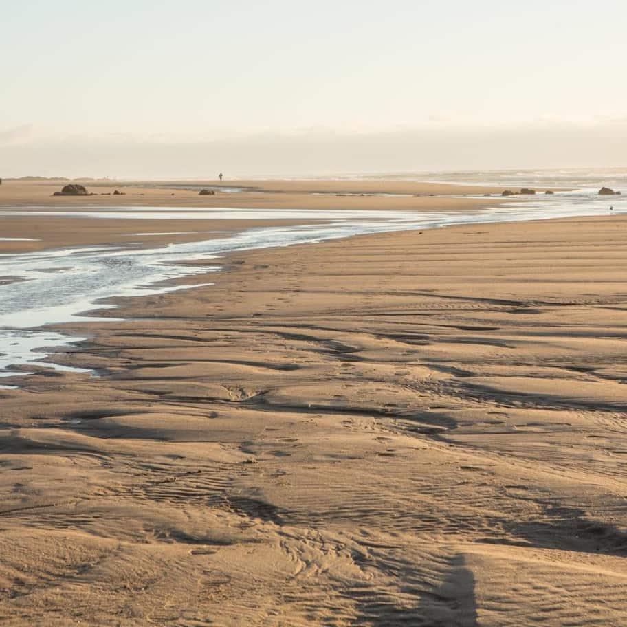 A wide sandy beach with gentle waves lapping at the shore.