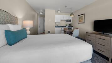 Une chambre d’hôtel avec un grand lit, un bureau, une télévision et une kitchenette.