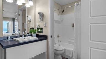 Un baño moderno con un lavabo blanco, espejo y zona de ducha.