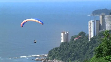Una persona haciendo paratrike sobre una zona costera, con edificios al fondo.