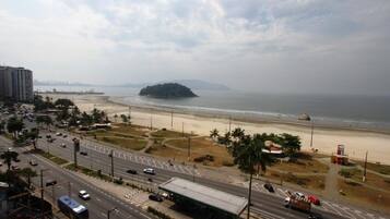 A coastal road with a beach and a small island in the distance.
