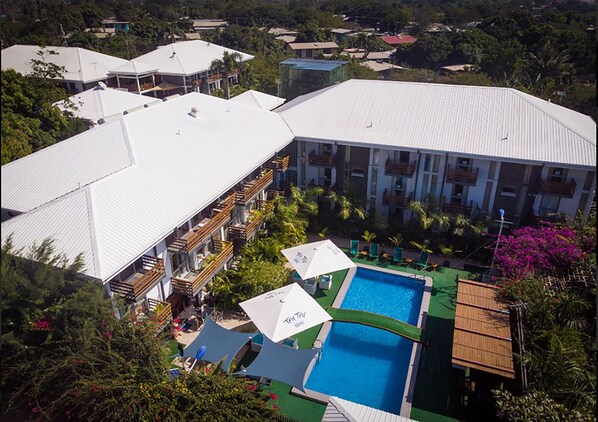 A resort with multiple buildings, a swimming pool, and outdoor umbrellas. - The Sanctuary Hotel and Spa (Port Moresby)
