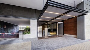 A modern building entrance with a tiled floor, a glass door, and a wooden panel wall. - Top Rentals Dorrego (Buenos Aires)