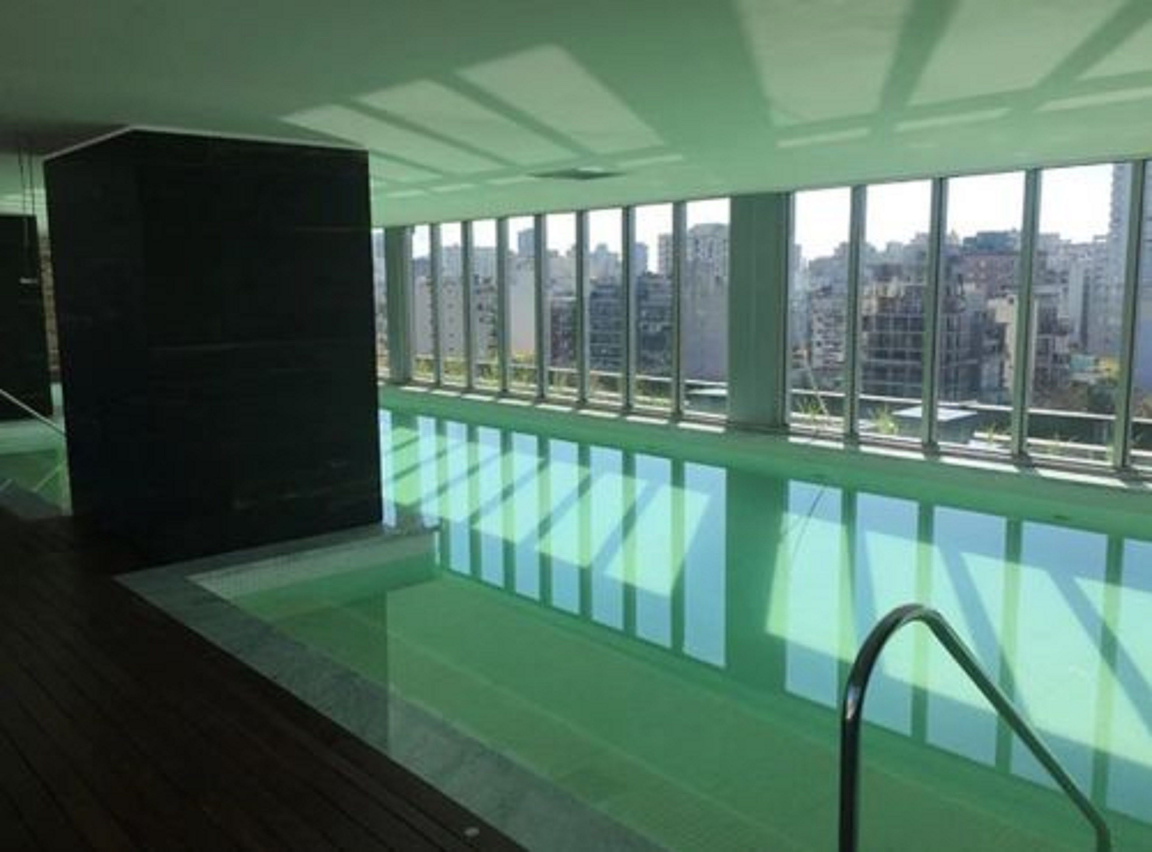 Une piscine intérieure moderne dotée de grandes fenêtres offrant une vue sur la ville.