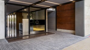 A modern building entrance with a glass door, a wooden wall, and a tiled floor. - Top Rentals Dorrego (Buenos Aires)