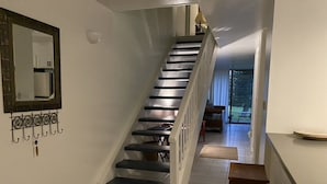 Uma escada com corrimão, um espelho na parede e um banco na base.