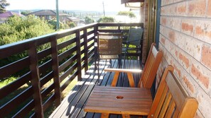 A wooden deck with a bench and a wicker chair, overlooking a residential area with houses and greenery. - 2/21 Montague Street - Boat Parking (BERMAGUI)