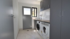 Una sala amb bugaderia que inclou una rentadora, una assecadora, un rentapeus i una finestra.