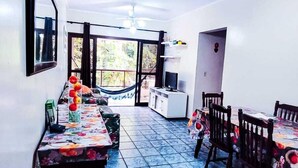 A dining area with a long table, chairs, a ceiling fan, and a view through glass doors.