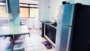 A kitchen with white cabinets, a refrigerator, a stove, and a sink.