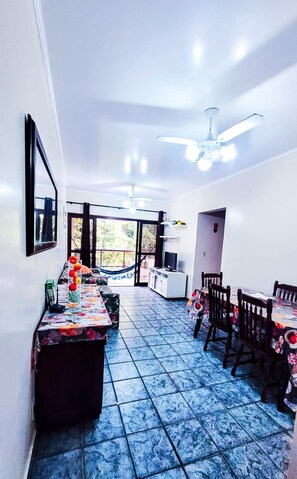 A dining area with a long table, chairs, a ceiling fan, and a view through glass doors.