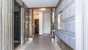 Un couloir avec des casiers d’un côté et une porte donnant sur une pièce de l’autre.