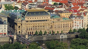 Un grand bâtiment historique doté d’un dôme imposant et d’une architecture classique, situé au bord d’une rivière, non loin d’un pont.