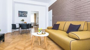 Un salon moderne avec un canapé jaune, un coin repas avec des chaises et un mur d’accent en briques.