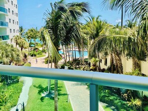 A pool area with palm trees, a pathway, and a building in the background. - Ocean front condo on Hollywood Beach !!! 1 bedroom / 3rd floor (Hollywood)