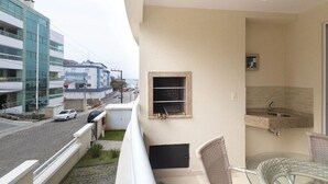 A balcony with a view of the street, a small sink, and a window with a shelf. - Vila Maior 207 - Praia de Bombas (Bombinhas)