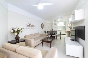 Uma sala de estar moderna com um sofá, mesa de centro e TV de tela plana na parede.