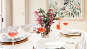 A dining table set with white plates, clear wine glasses, and a vase with pink flowers. - That Pink House! – pets welcome (Bowral)
