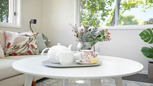 A round white table with a teapot, cups, and a vase with flowers. - That Pink House! – pets welcome (Bowral)