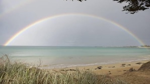 Ein Strand mit einem Regenbogen über dem Wasser.