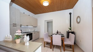 A modern kitchen with a dining area, wooden ceiling, and a small potted plant. - Villa Pocelje a beautiful view of nature and sea.  (Omiš)