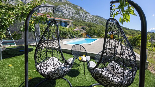 A poolside area with hanging chairs and a view of mountains. - Villa Pocelje a beautiful view of nature and sea.  (Omiš)