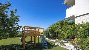 A wooden play structure with a ladder, a white building, and a clear blue sky. - Villa Pocelje a beautiful view of nature and sea.  (Omiš)