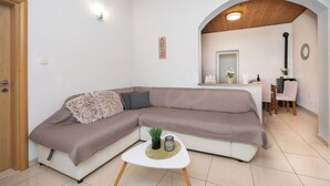 A modern living room with a sectional sofa, a small white table, and a kitchen area in the background. - Villa Pocelje a beautiful view of nature and sea.  (Omiš)
